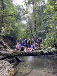 Best time to visit panama with your kids. Children in a rainforest sitting on a log on top of a creek.
