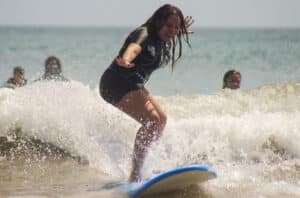 A smiling girl riding a wave during a surf lesson in Panama, enjoying an all-inclusive family vacation at one of the best places for family adventure holidays.