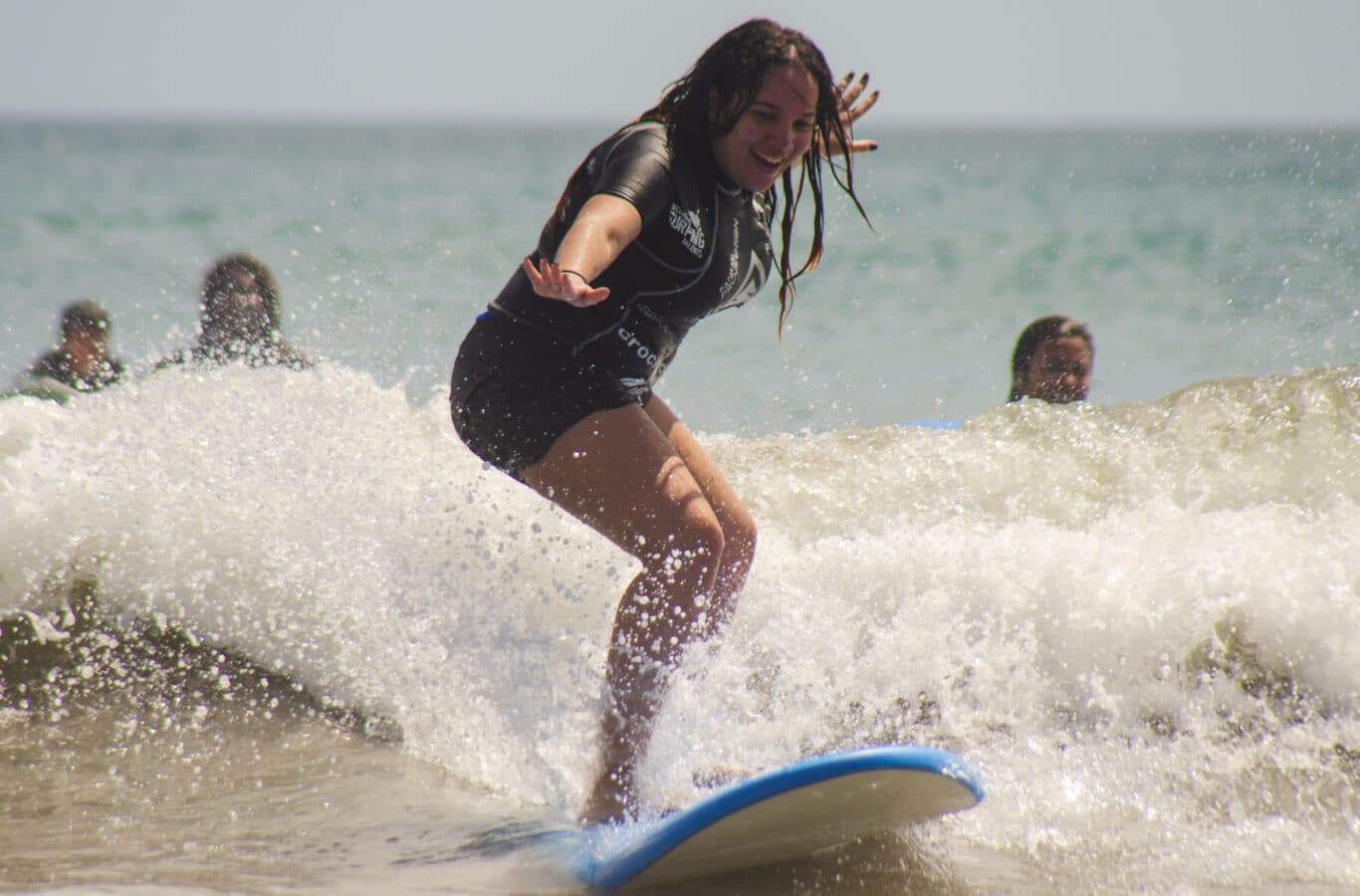family-vacation-panama-surf-lesson-girl-riding-wave A smiling girl riding a wave during a surf lesson in Panama, enjoying an all-inclusive family vacation at one of the best places for family adventure holidays.